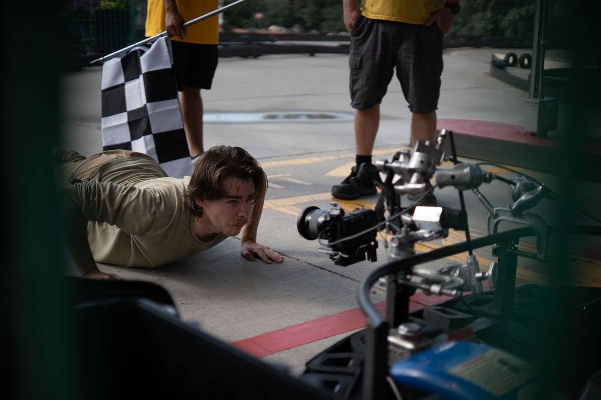 Actor lining up a low shot with a rigged camera at a go-kart track