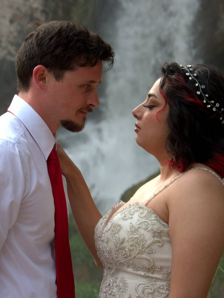 Bride and groom face to face by a waterfall