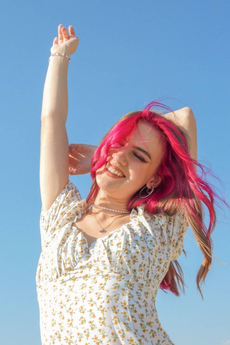 Senior with pink hair against a blue sky