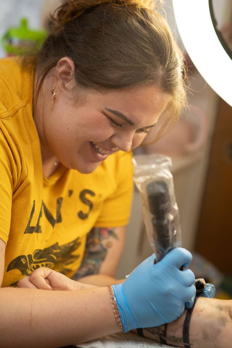 Tattoo artist laughing while she works